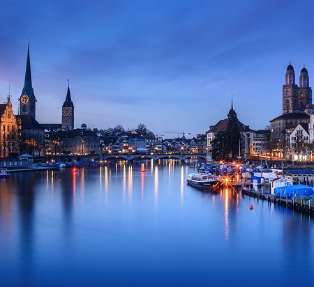 Blue hour shot of Zurich, Switzerland. The image shows the river Limmat and the three churches Fraumünster, St. Peter and Grossmünster. (© kuhnmi, CC BY 2.0)